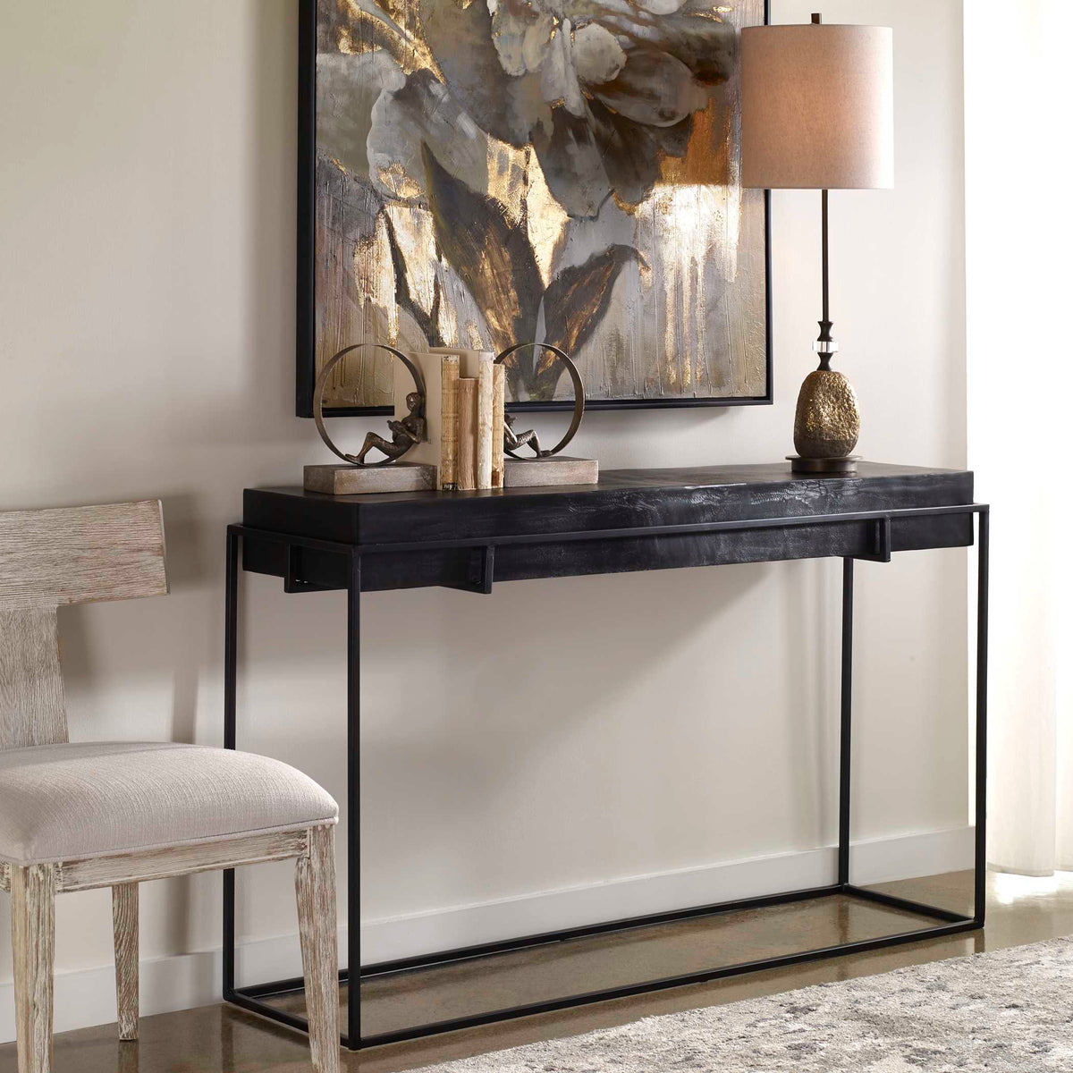 Uttermost 25110 Telone modern console table styled with a table lamp, art and books beside a chair