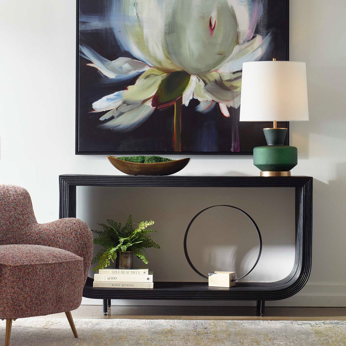 Uttermost 50055 Compton rattan console table styled with a lamp, plant and books beside an upholstered chair