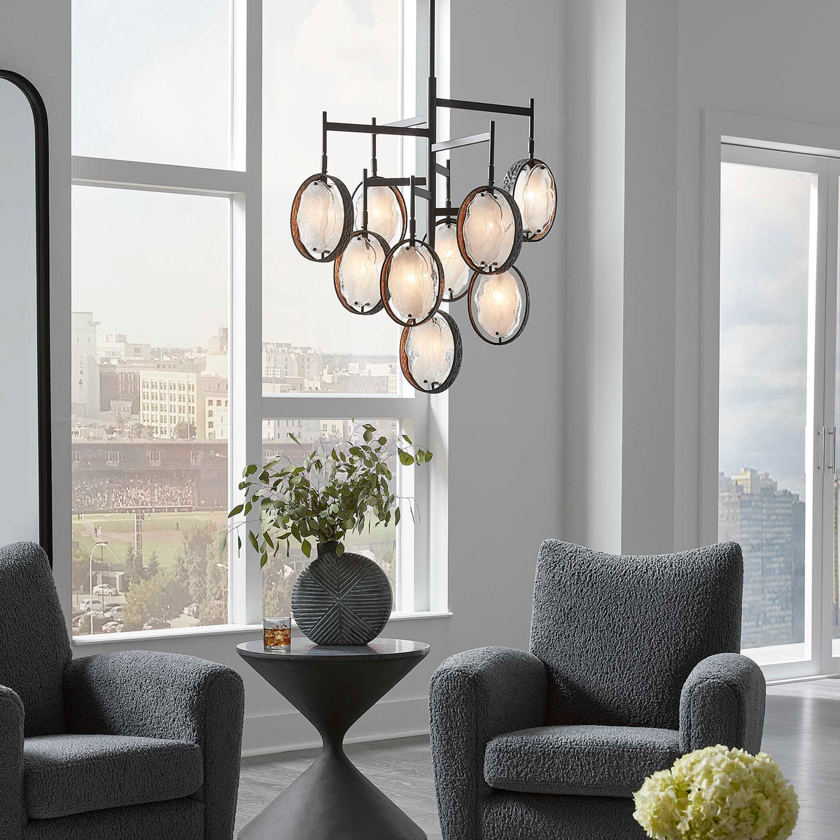 Maxin glass ring chandelier in a loft living room with tall windows and gray boucle chairs
