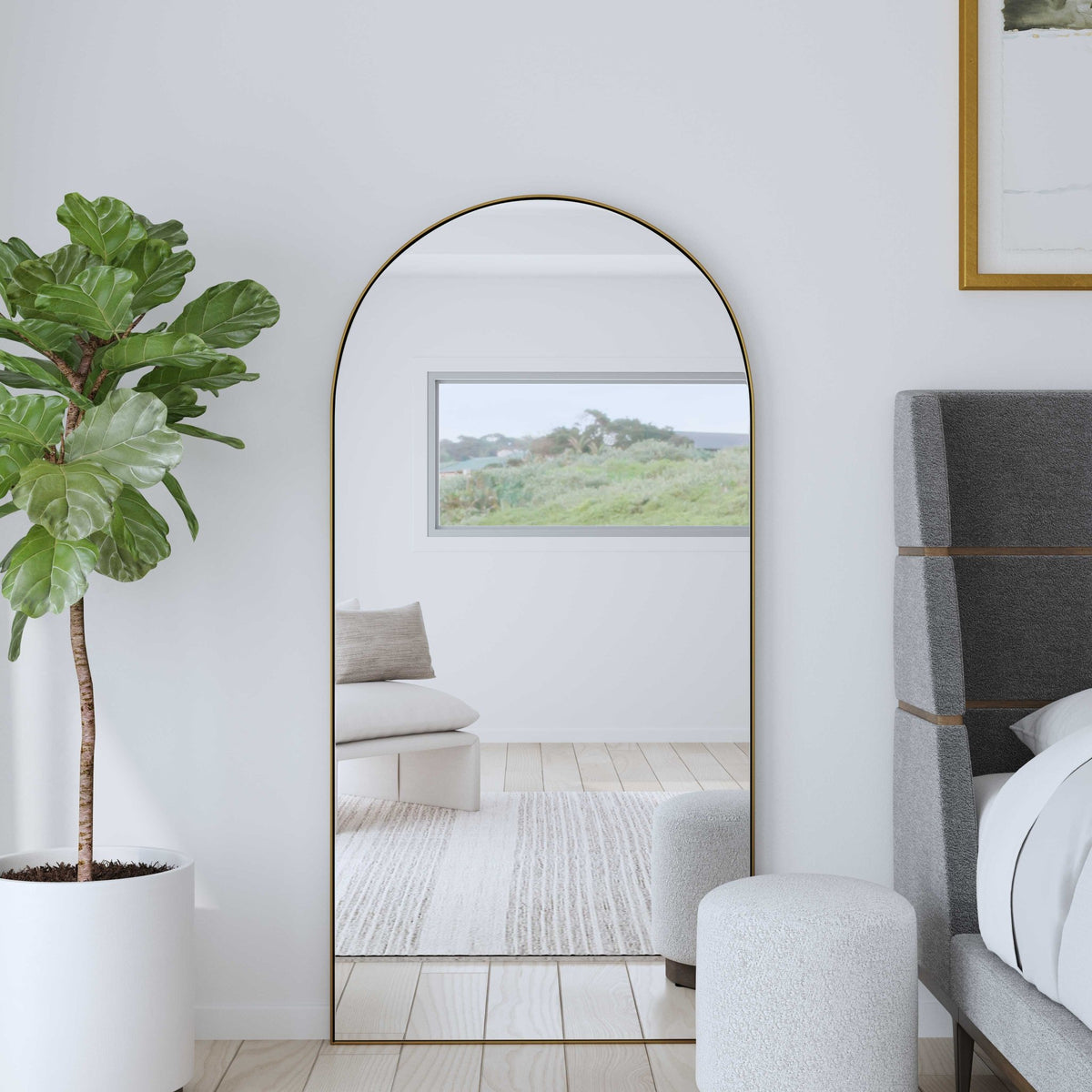 Uttermost 09841 Crosley arch mirror leaning in a bedroom beside an upholstered bed