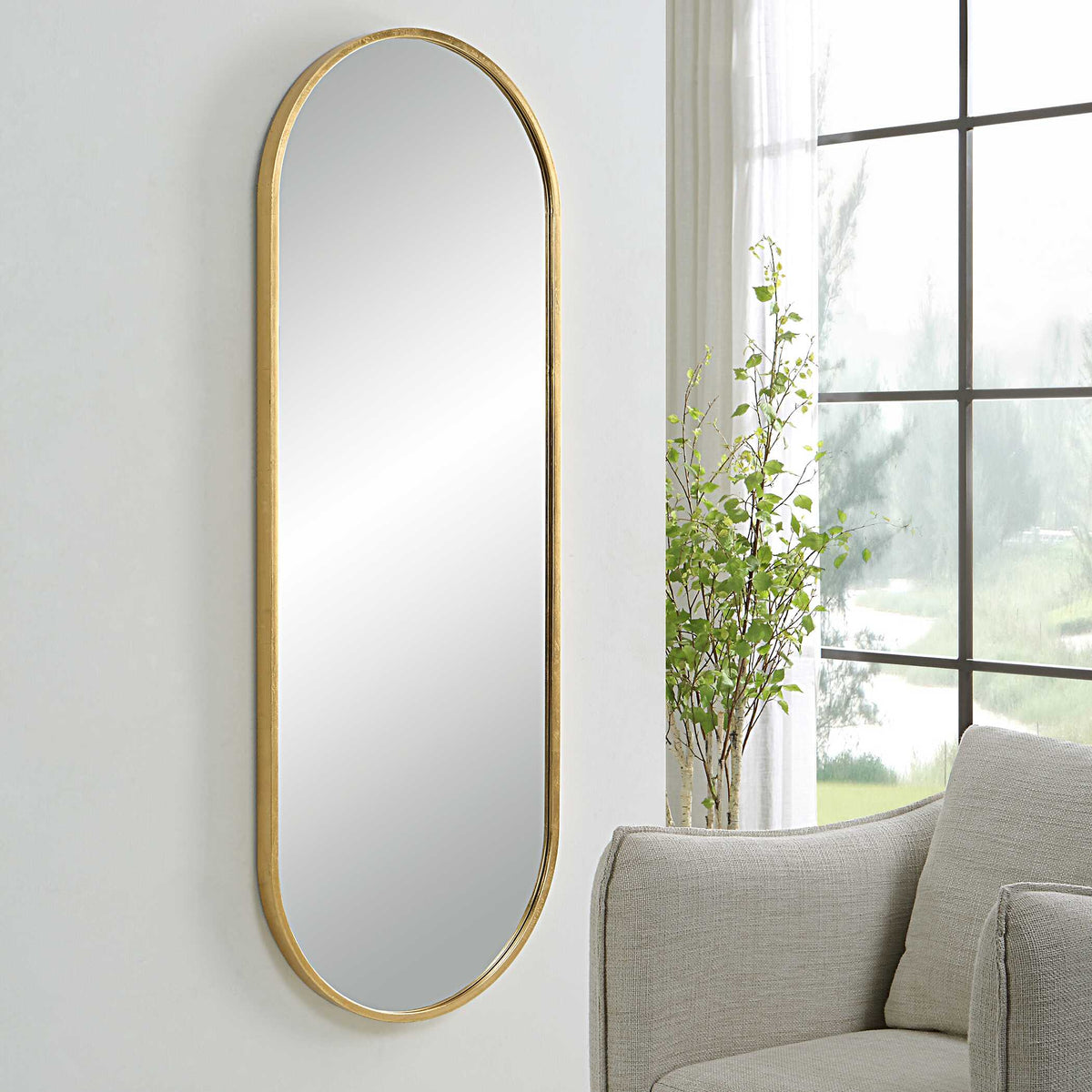 Uttermost 09844 Varina tall mirror hung beside a window above a gray armchair