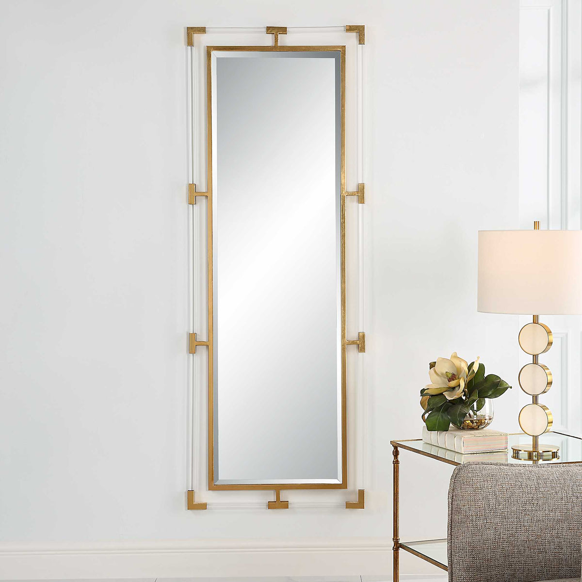 Uttermost 09926 Balkan tall gold mirror beside a gray armchair and glass side table