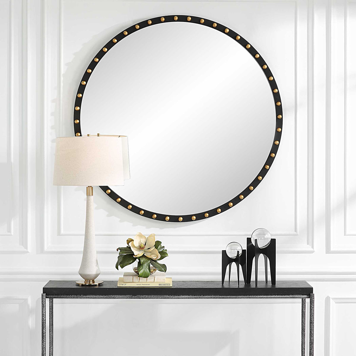 Uttermost 09949 Sele oversized round mirror over a console table with a lamp and flowers