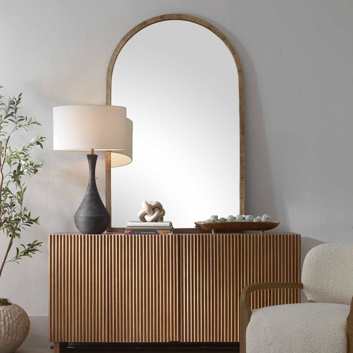 Uttermost 08273 Vestry collection arch mirror above a fluted wood credenza with a table lamp