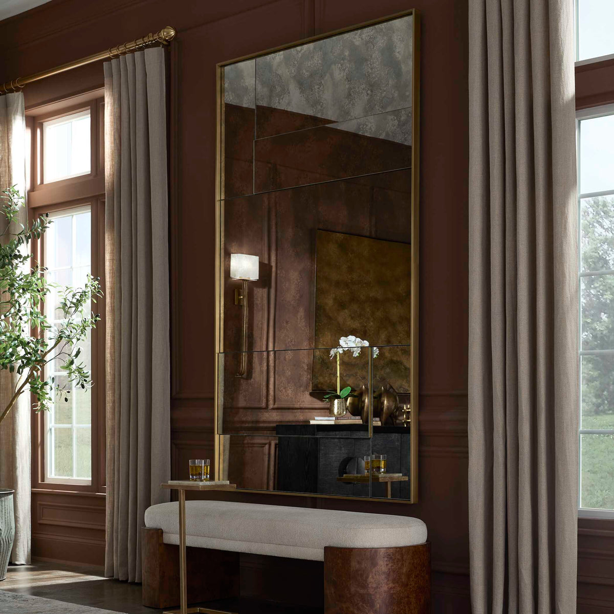 Uttermost 08306 Rally collection antiqued mirror above a cream bench in a dark wood paneled room