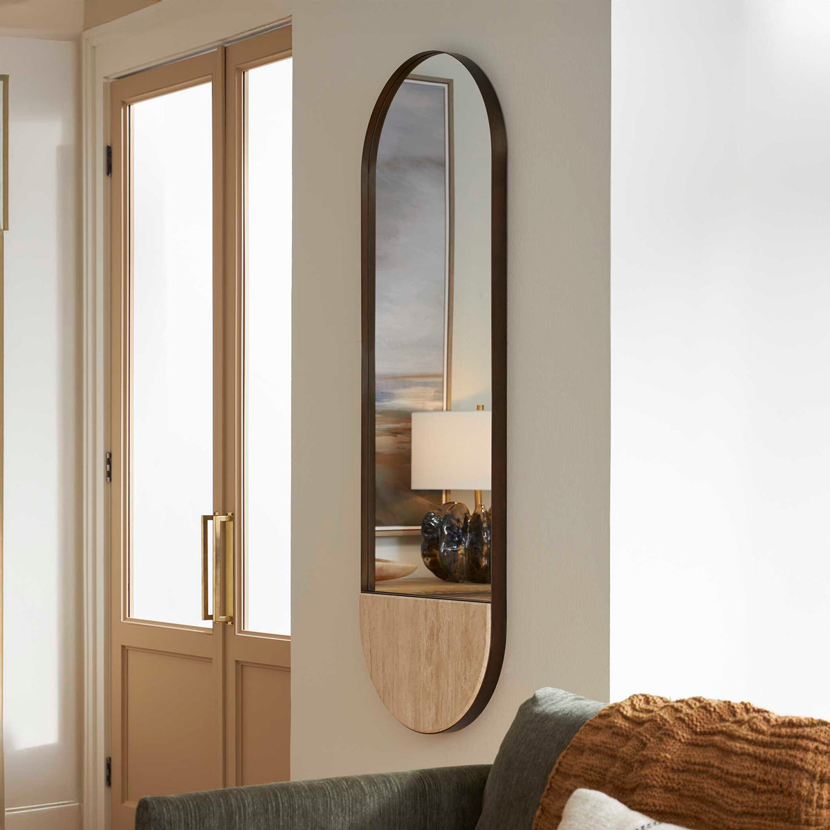 Uttermost 08293 Russo collection oval mirror in an entry beside glass doors and a sofa