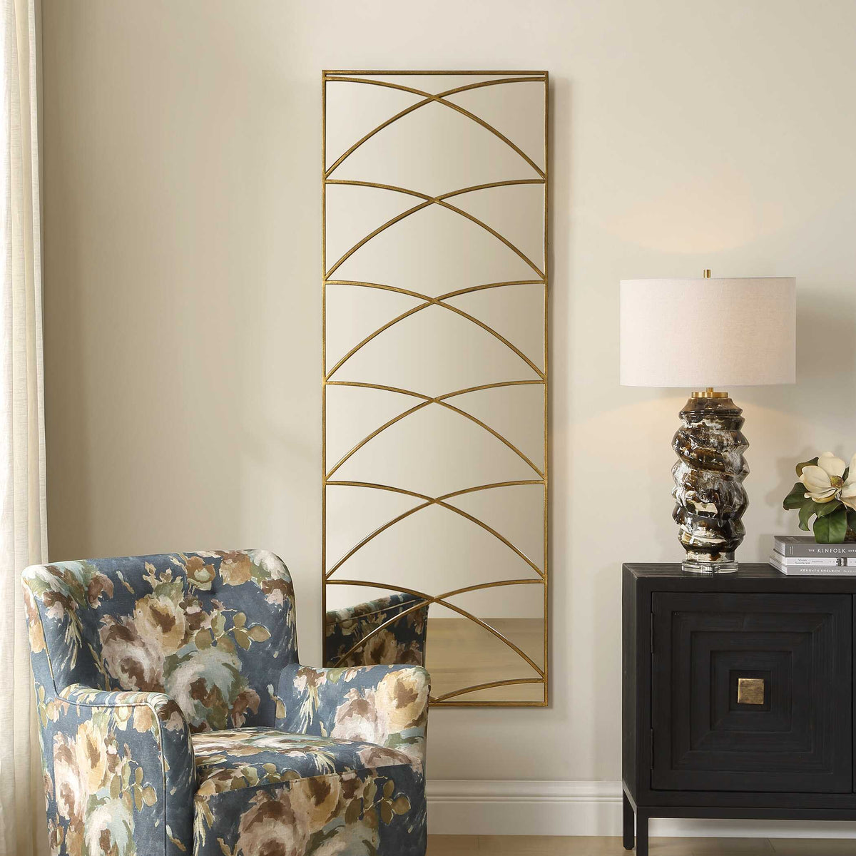 Uttermost 08320 Crossed Up collection mirror beside a floral armchair and dark cabinet with a lamp