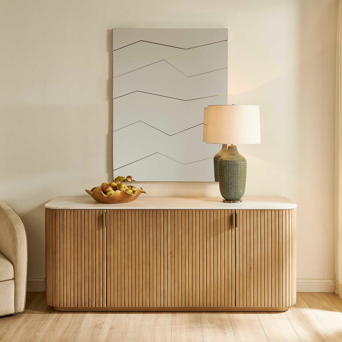 Uttermost 08403 Fracture segmented mirror above a fluted wood credenza with a cream top and table lamp