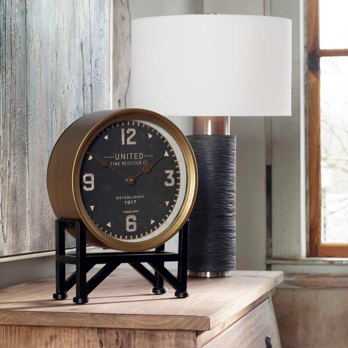 Vintage Old Money desk clock on a wood chest beside a white shade table lamp