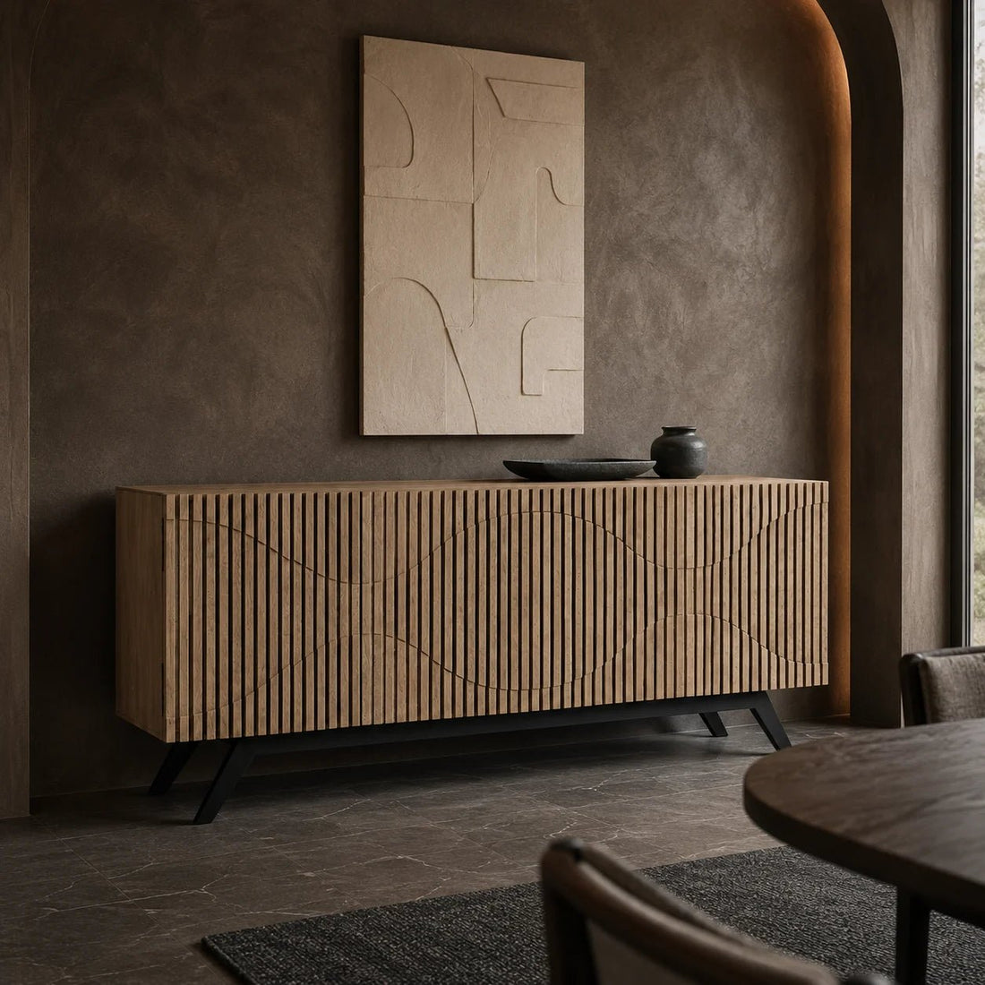 Illusion Sideboard with Iron Base in Bleached Walnut w/ Matte Black Frame by Noir (GCON244BW). A sleek metal base supports a decoratively carved walnut sideboard, with etched grooves that create an intriguing feeling of movement. Shown in a bedroom.