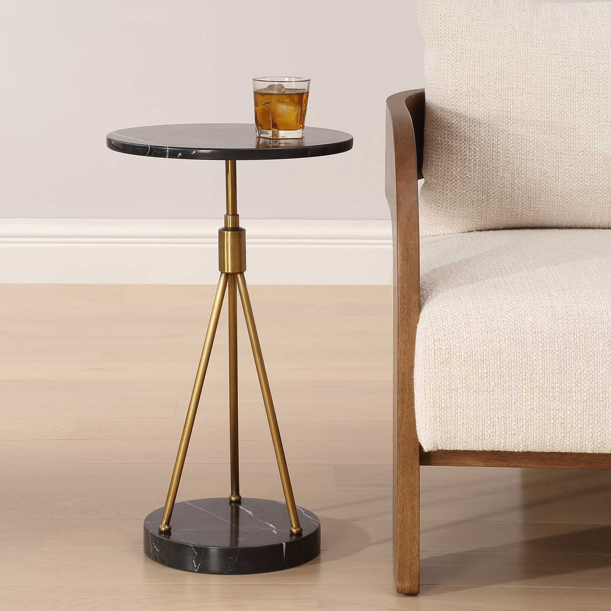 Uttermost 50066 Rosston drink table beside a cream upholstered armchair, holding a glass of whiskey