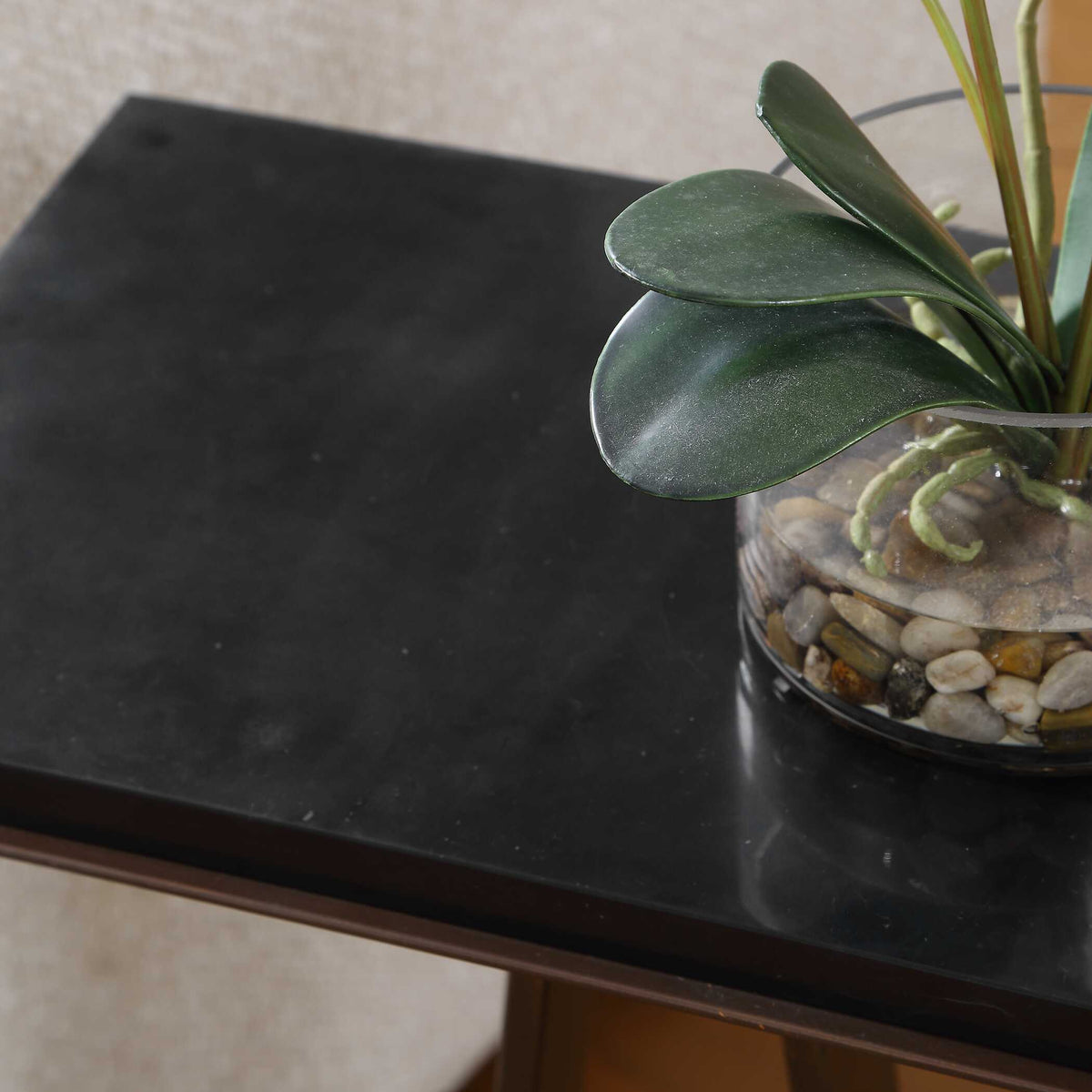 Close-up of a black marble tabletop on a dark bronze iron frame beside a potted plant, Dark Academia