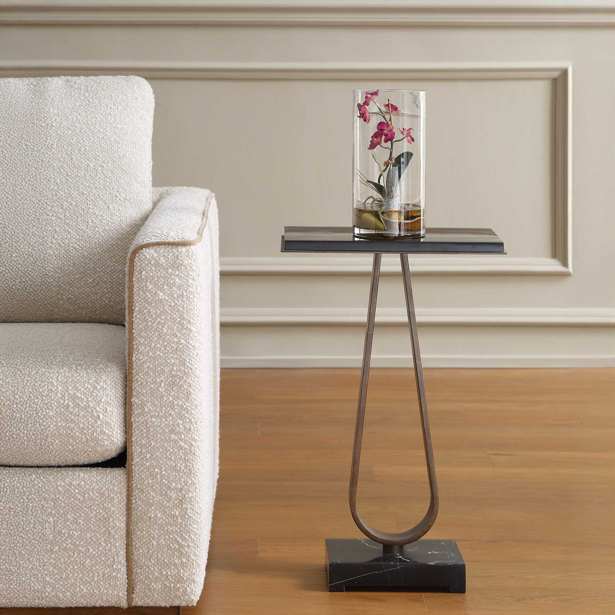 Uttermost 51128 Galloway accent table with a potted orchid beside a cream boucle armchair, paneled wall