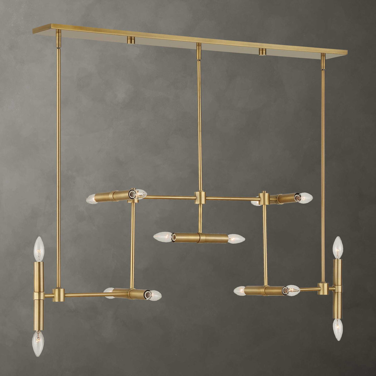 Cadre antique brass linear pendant light against a gray plaster wall