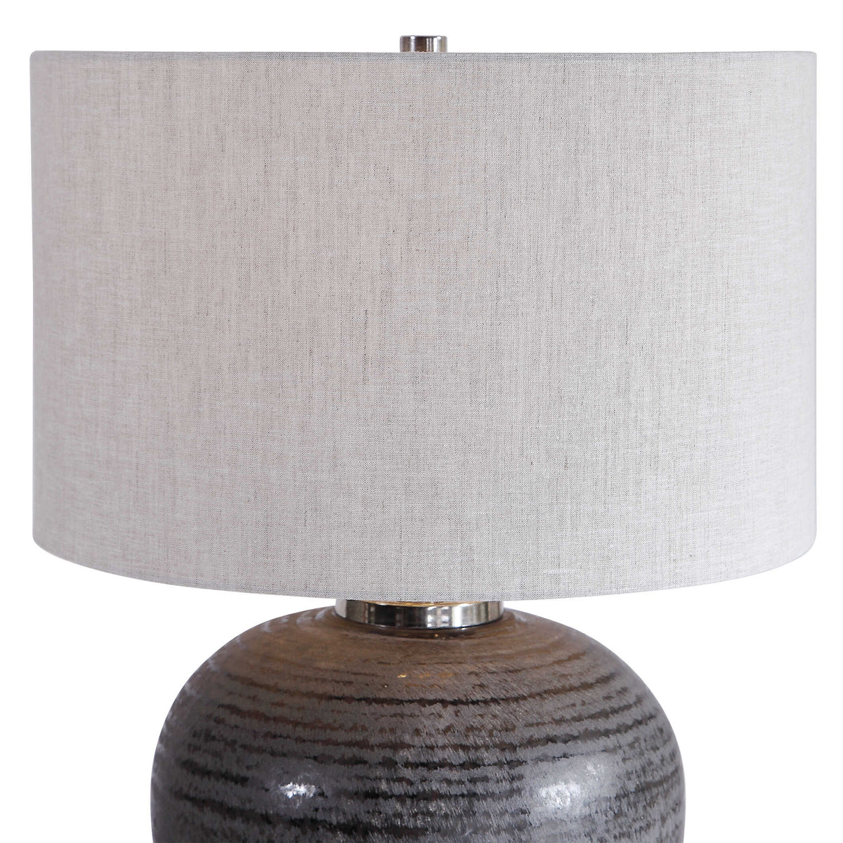 Close up of the natural linen drum hardback shade and brushed nickel neck on a Japandi charcoal ceramic lamp