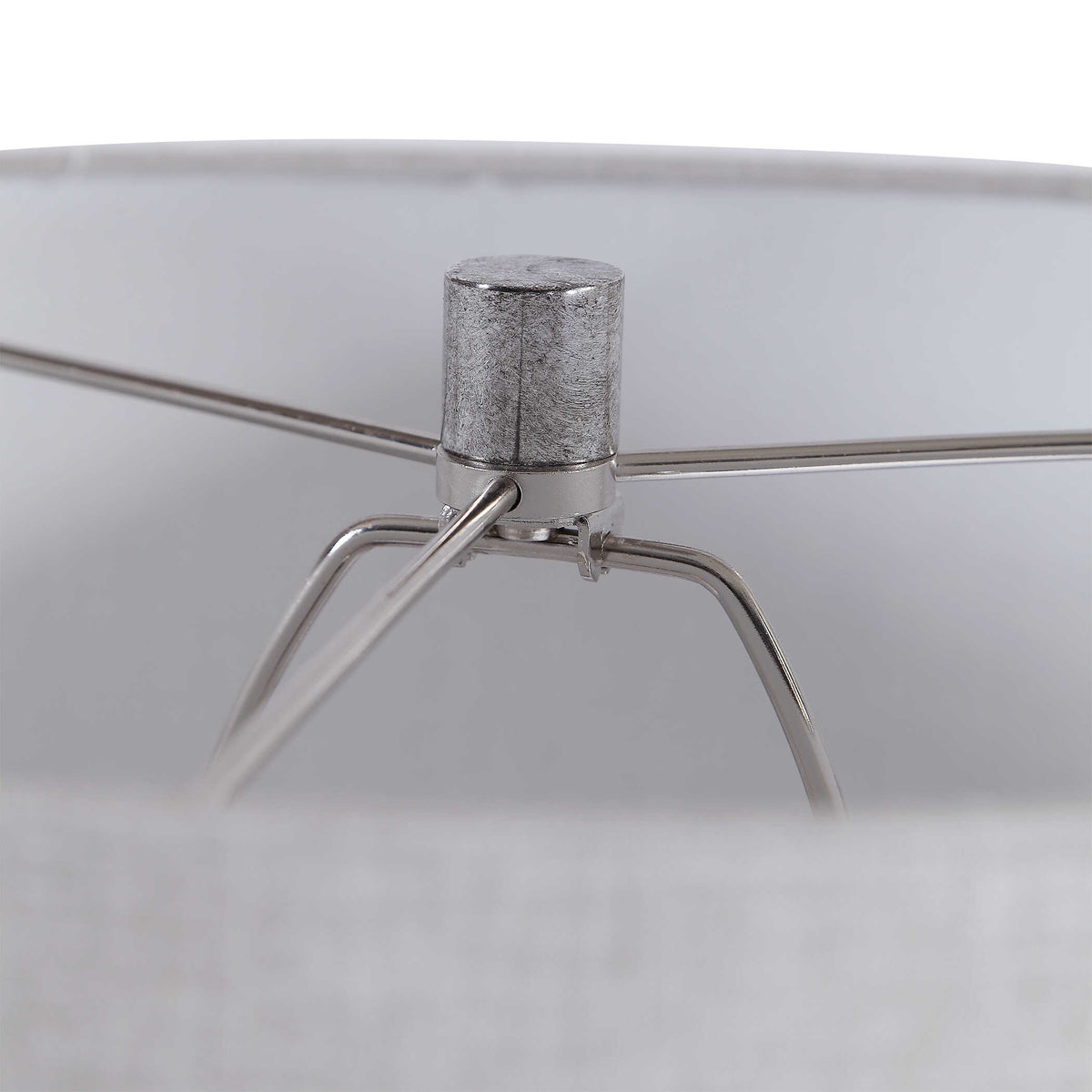 Inside the natural linen shade of a gray ceramic table lamp, brushed nickel harp and finial