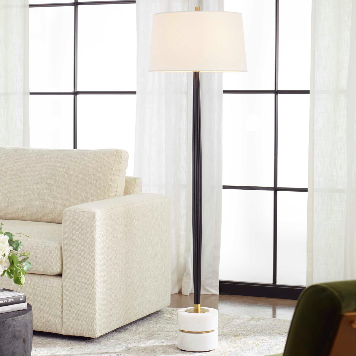 Miraz channeled cast iron floor lamp beside a cream sofa in front of steel framed windows