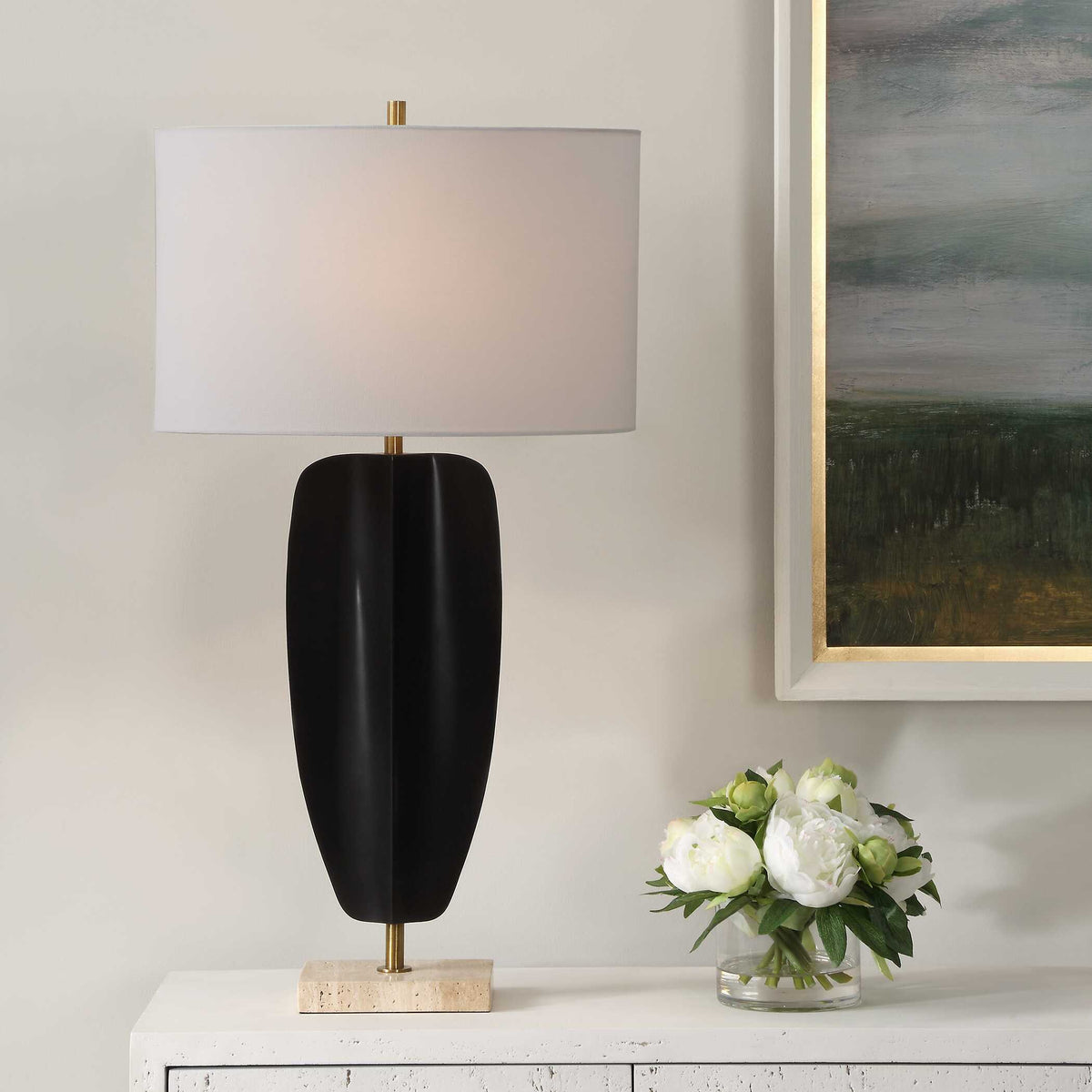 Kure matte black iron table lamp on a white console beside white peonies and a landscape painting