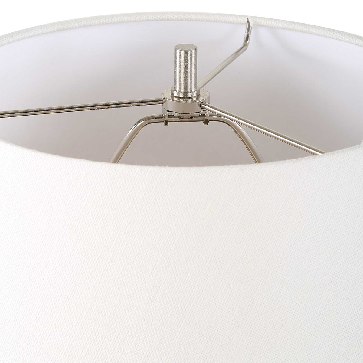 Plated nickel finial and harp under the white round hardback shade of a ceramic bedside lamp