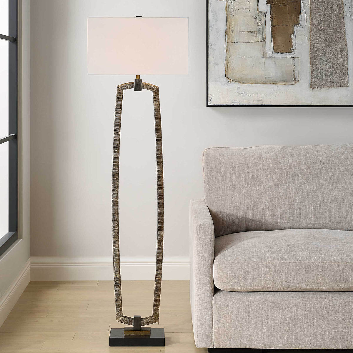 Relic antique gold floor lamp beside a light gray sofa under neutral abstract art