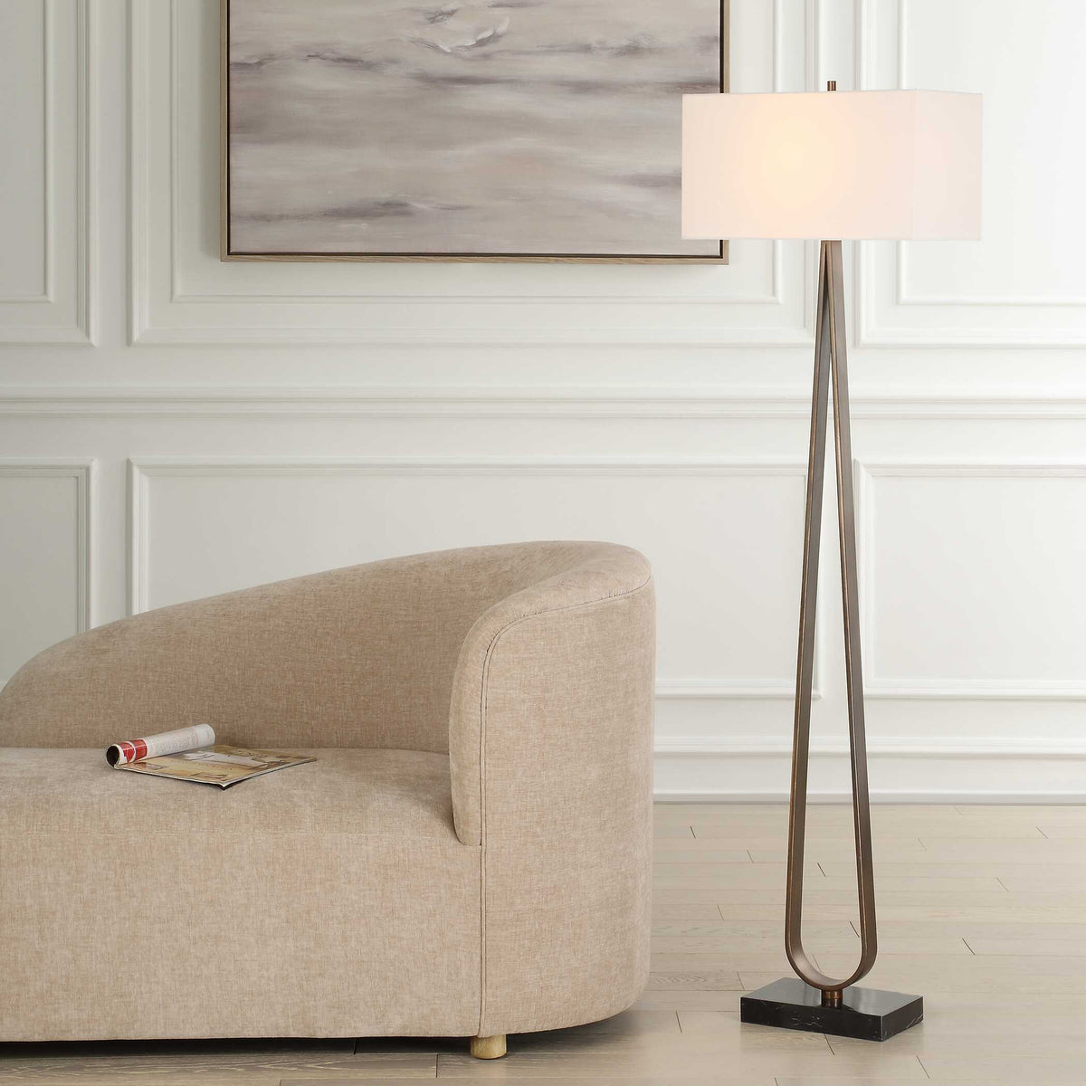 Galloway black marble floor lamp beside a tan curved sofa against white paneled walls