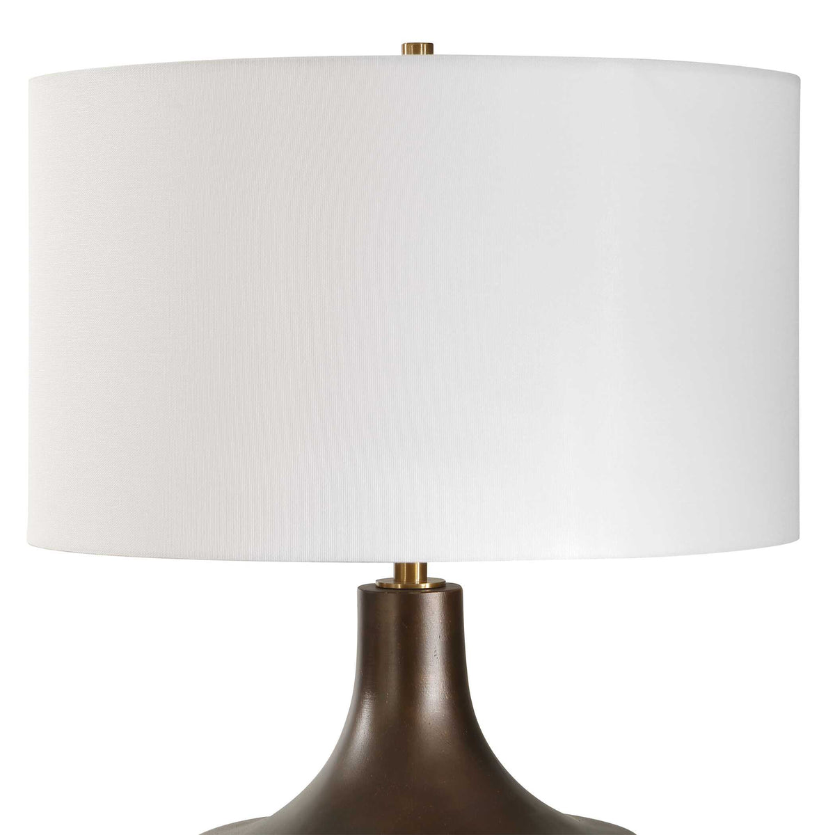 White round drum hardback shade over the tapered neck of a warm bronze nightstand lamp