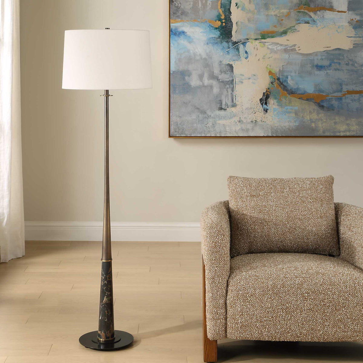 Tapered dark bronze iron standing lamp with a black marble section beside an armchair and abstract art