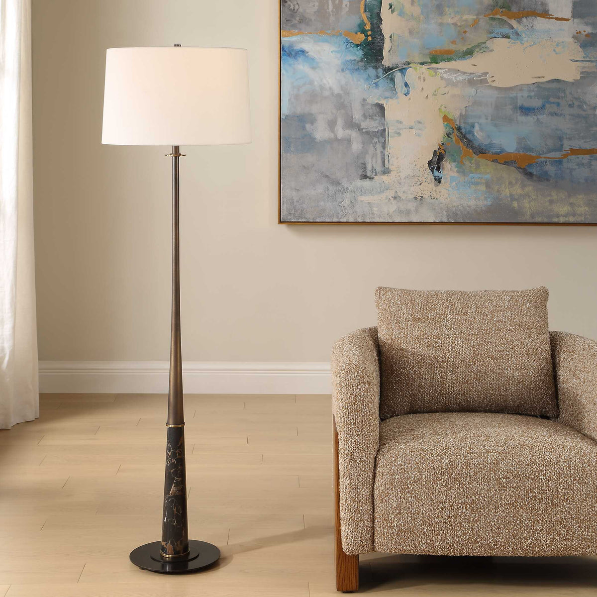 Tallarico dark bronze and black marble floor lamp beside a tan boucle armchair in a living room