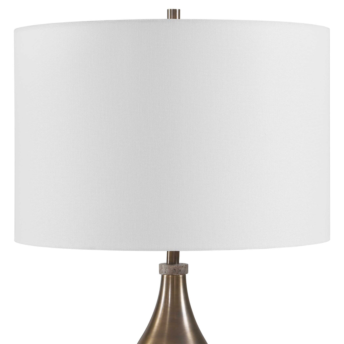 Close view of the white linen drum shade, travertine stone collar and antique brass finial