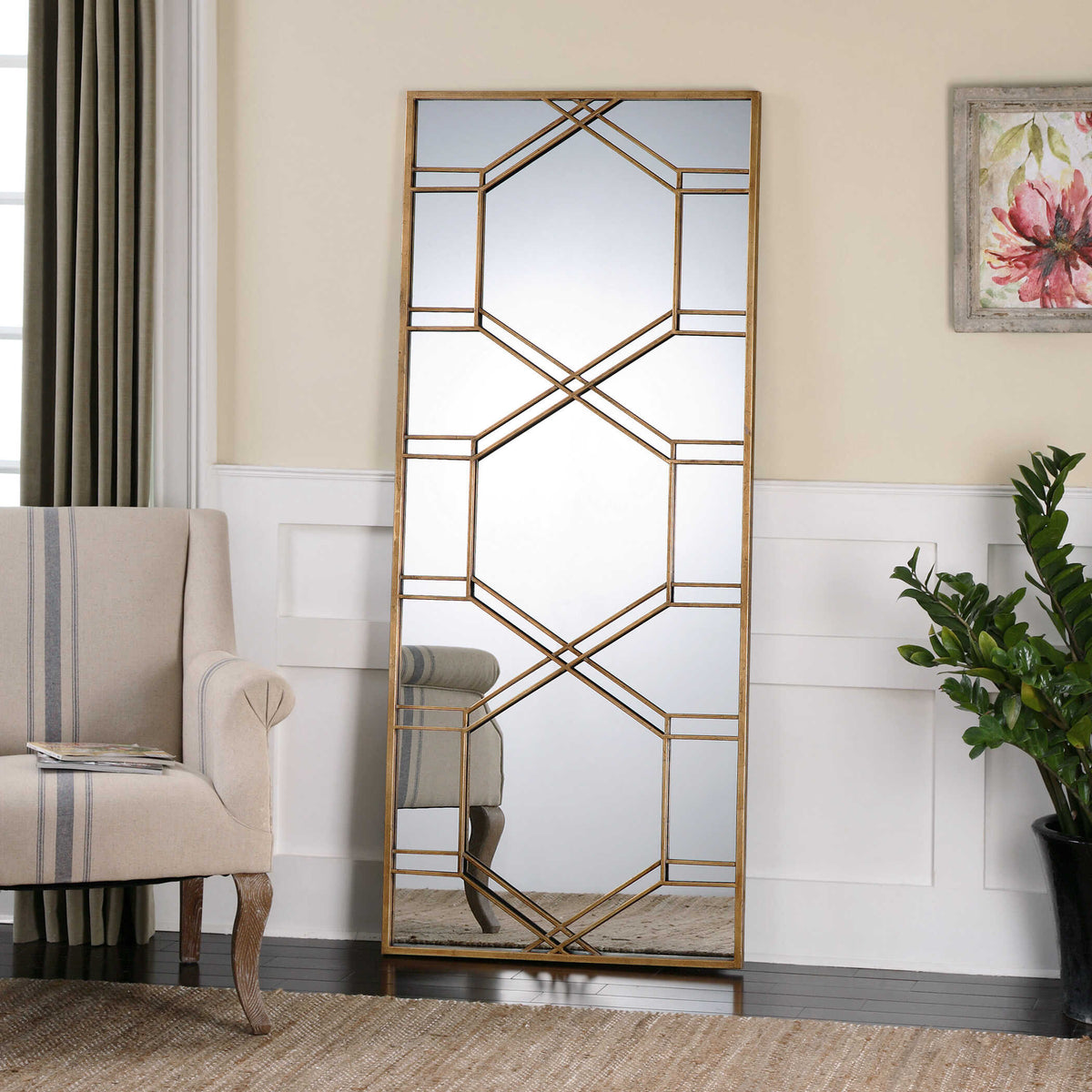 Uttermost 13922 Kennis gold leaf leaner mirror against a paneled wall beside an armchair