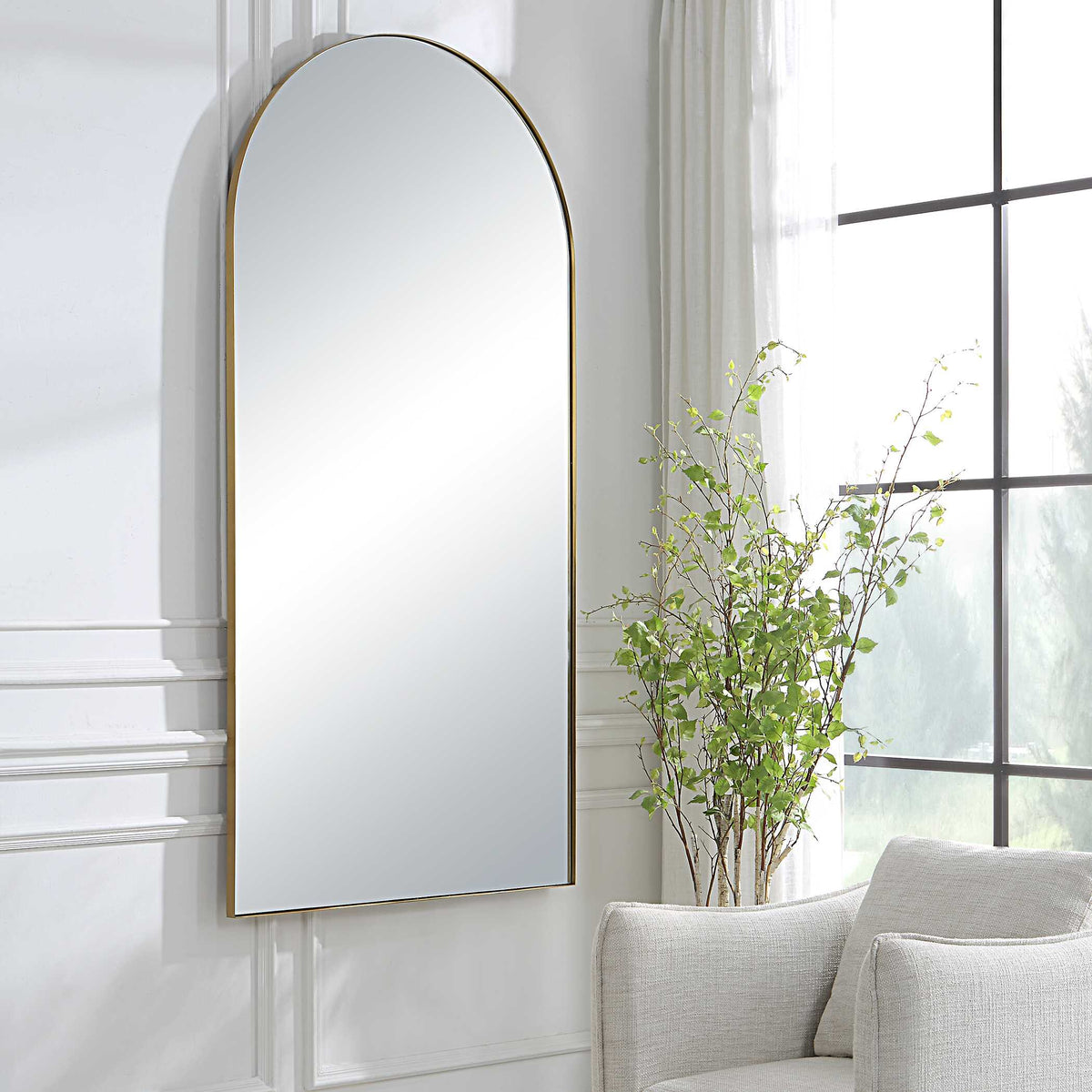Large arched wall mirror for the living room, hung by a window with an armchair