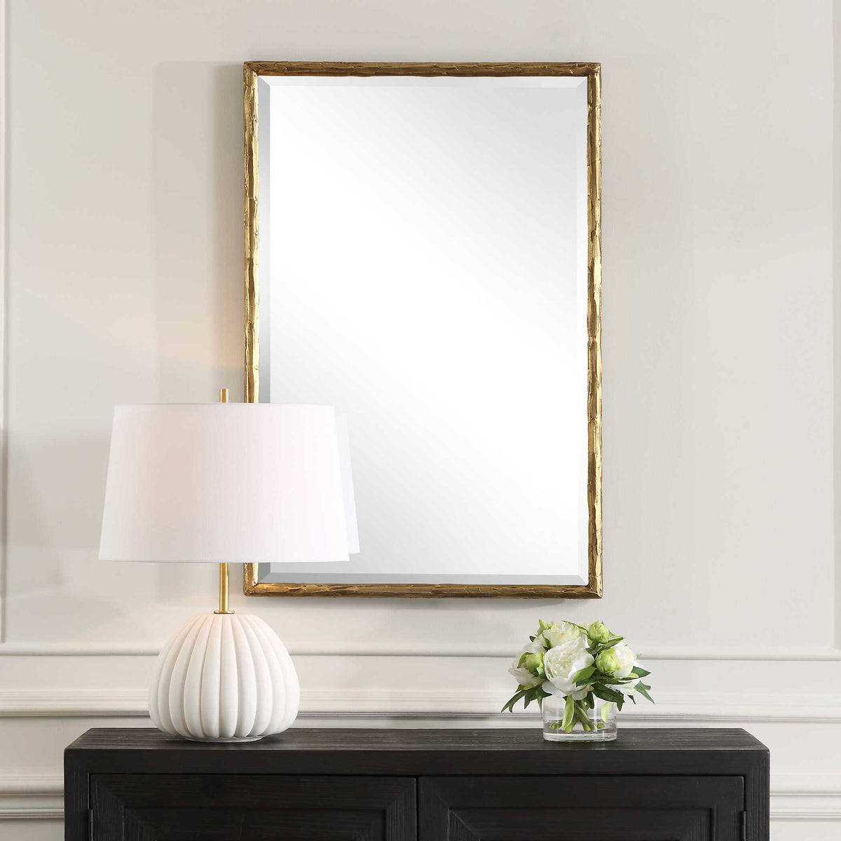 Uttermost 09993 Sutton vanity mirror over a dark credenza with a white ribbed lamp