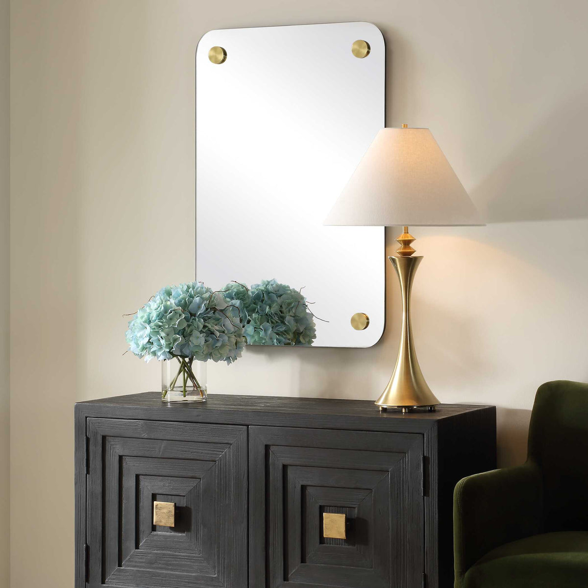 Frameless vanity mirror over a credenza with a brass table lamp, angled view