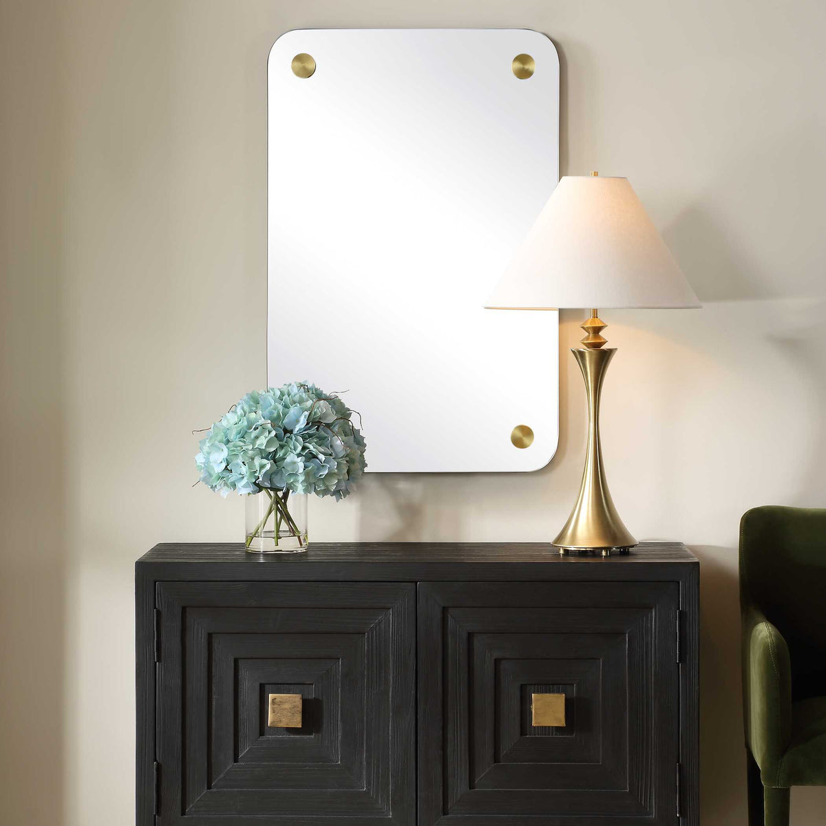 Uttermost 08265 Hamrick collection frameless mirror above a dark cabinet with a lamp and hydrangeas