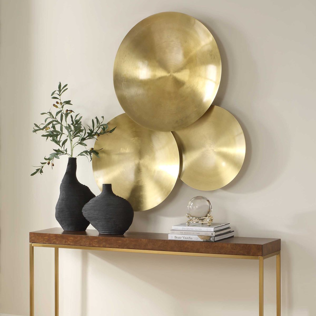 Dark Academia round wall sculptures in gold over a console, styled with black ribbed vases