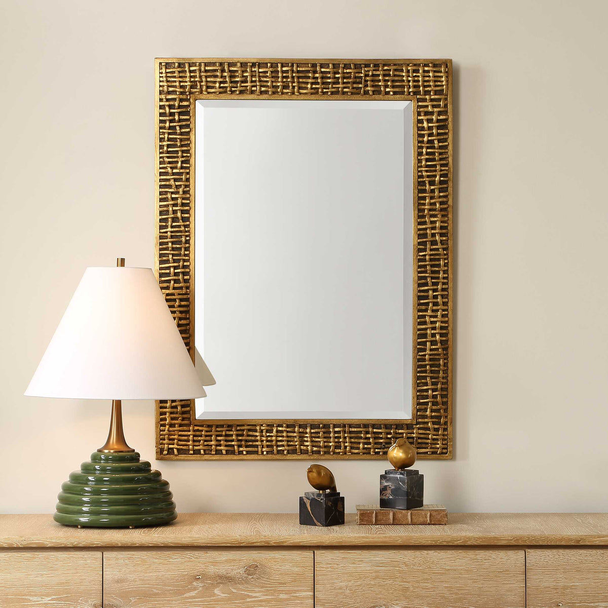 Uttermost 08288 Woven In Time collection gold mirror above a wood credenza with a table lamp