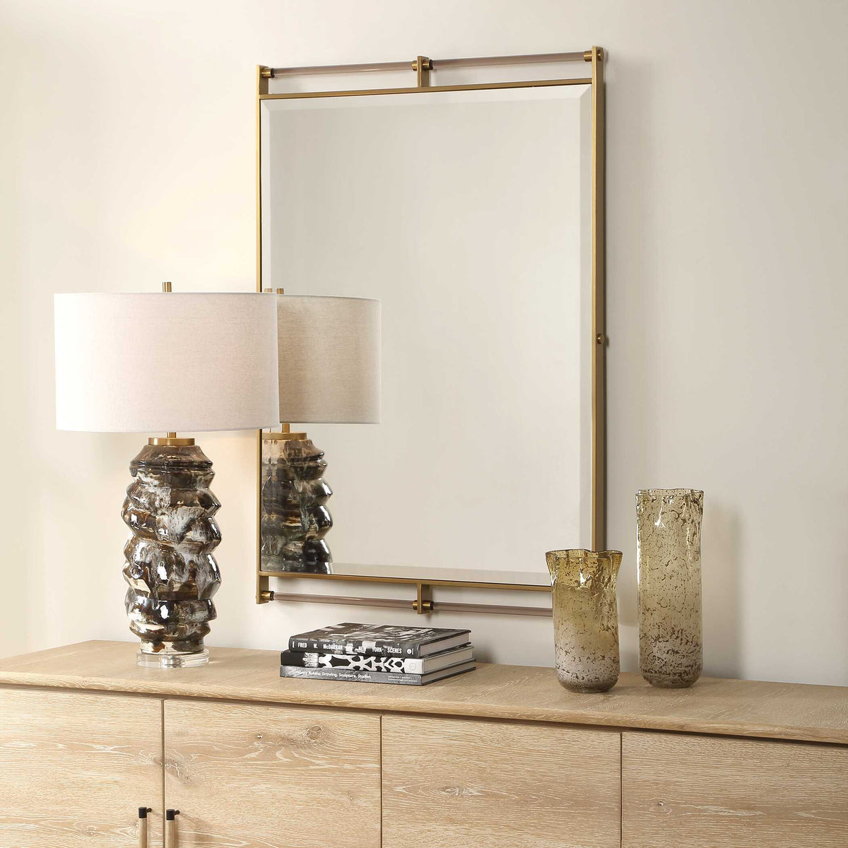 Clean lined brass frame mirror with amber accent bars, angled over a credenza