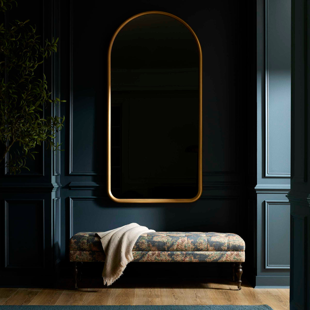 Uttermost 08367 Marvell collection mirror on a dark paneled wall above a floral tufted bench