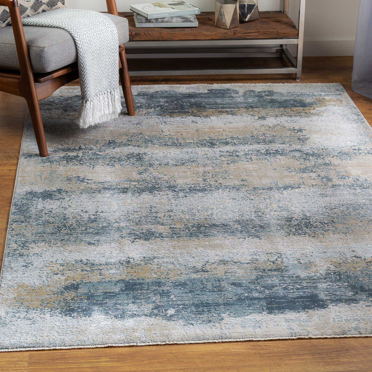 Bremen gray and blue abstract rug in a living room with a wood accent chair and shelf