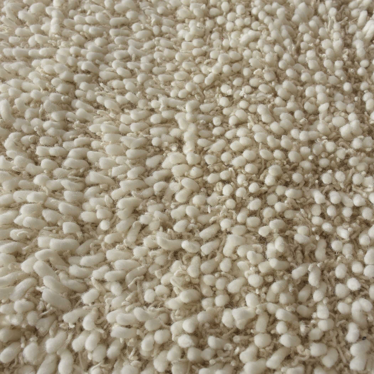 Close-up of thick nubby ivory wool pile, a plush organic modern bedroom rug