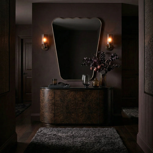 Antiqued brass wavy mirror in a moody entryway