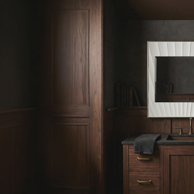 A short video of a bathroom vanity with wooden cabinets, black countertop, and decorative mirror.