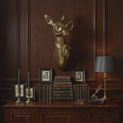 Product video of a Margie the Doe scarf-adorned brass antique gold wall mount styled as gold-wall-decor above a wood cabinet with books and framed art