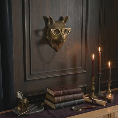 product video of Eloise the Fox bespectacled brass antique gold wall mount styled as gold-wall-decor on a dark paneled wall with books, candles, and writing desk accents